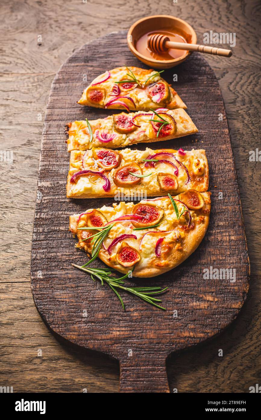 French Tarte Flambee (Flammkuchen) with figs, red onions, soft goat cheese and honey Stock Photo