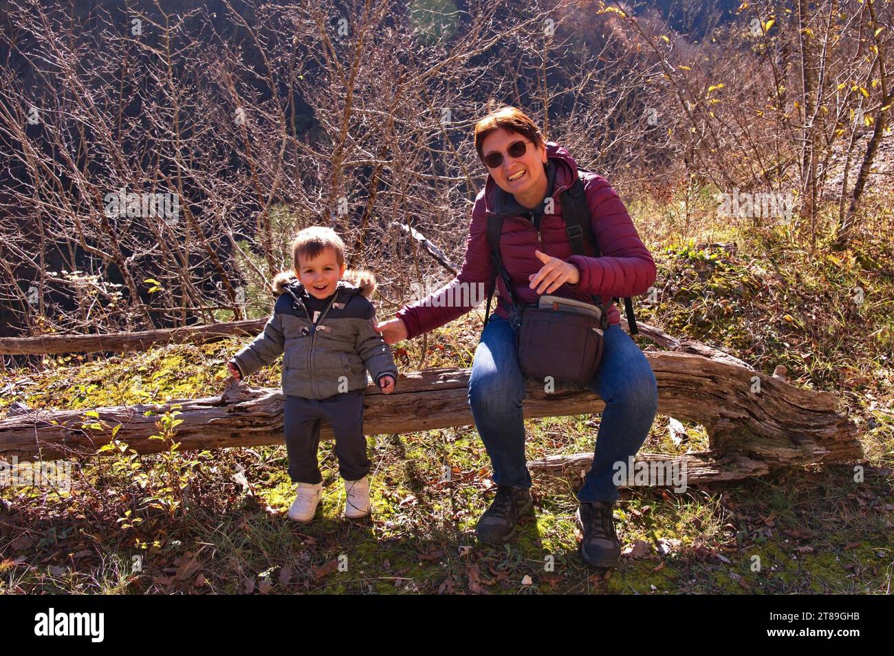 Grandmother and grandchild sitting on the tree trunk in the forest Stock Photo