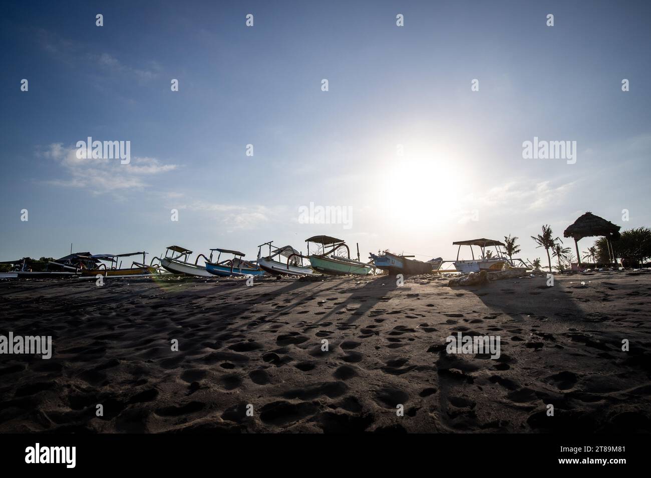 Black sand beach in Bali, natural with temples, boats (jukung) and waves at sunrise. Tropical environment in Indonesia in the morning Stock Photo