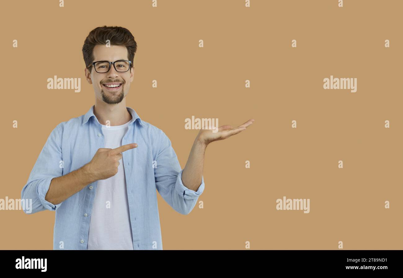 Happy teacher or student smiling and pointing at something he is holding in hand Stock Photo