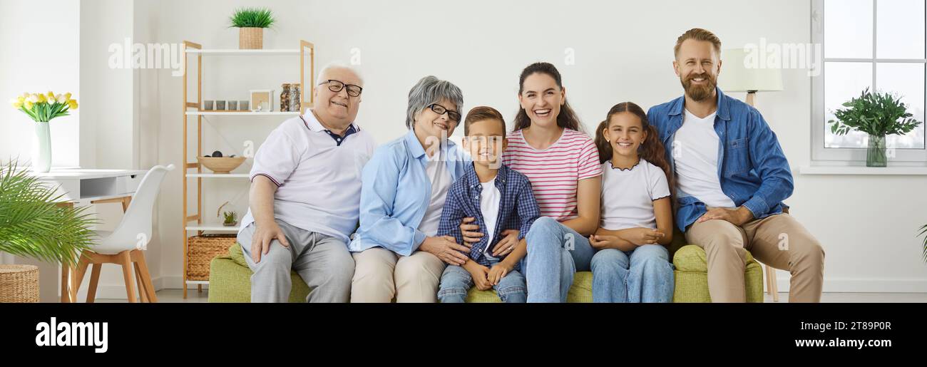 Banner background with a group portrait of a happy family sitting on the sofa at home Stock Photo