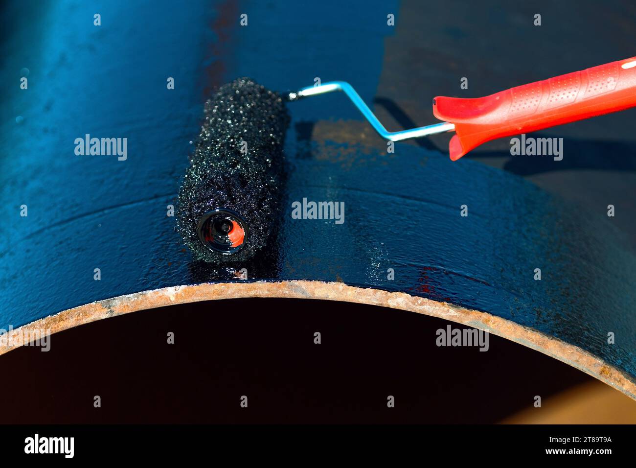 Metal pipe is painted with paint roller with black paint or bitumen