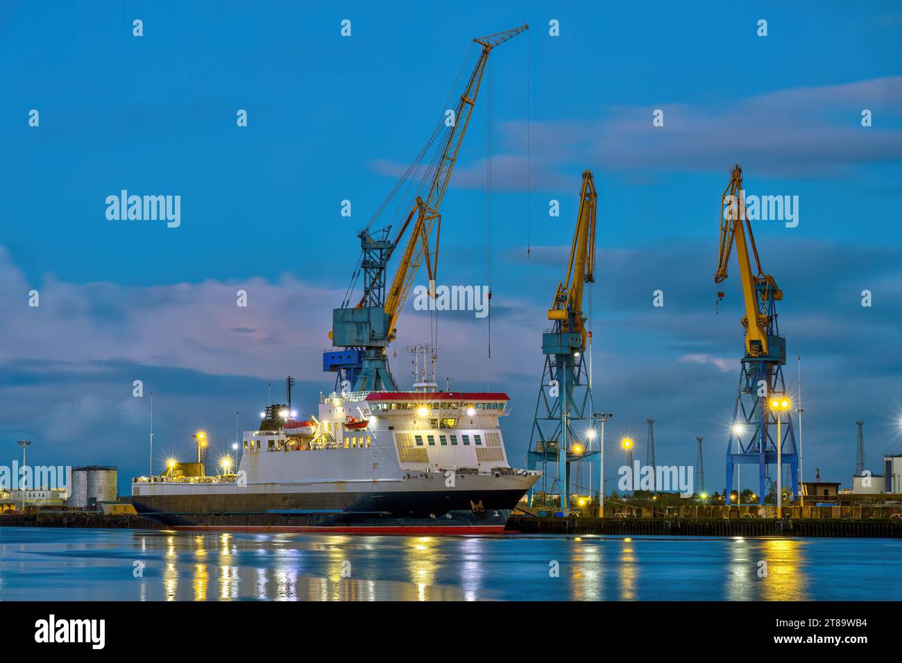 Three yellow and blue cranes at dusk seen in the port of Belfast, Northern Ireland Stock Photo