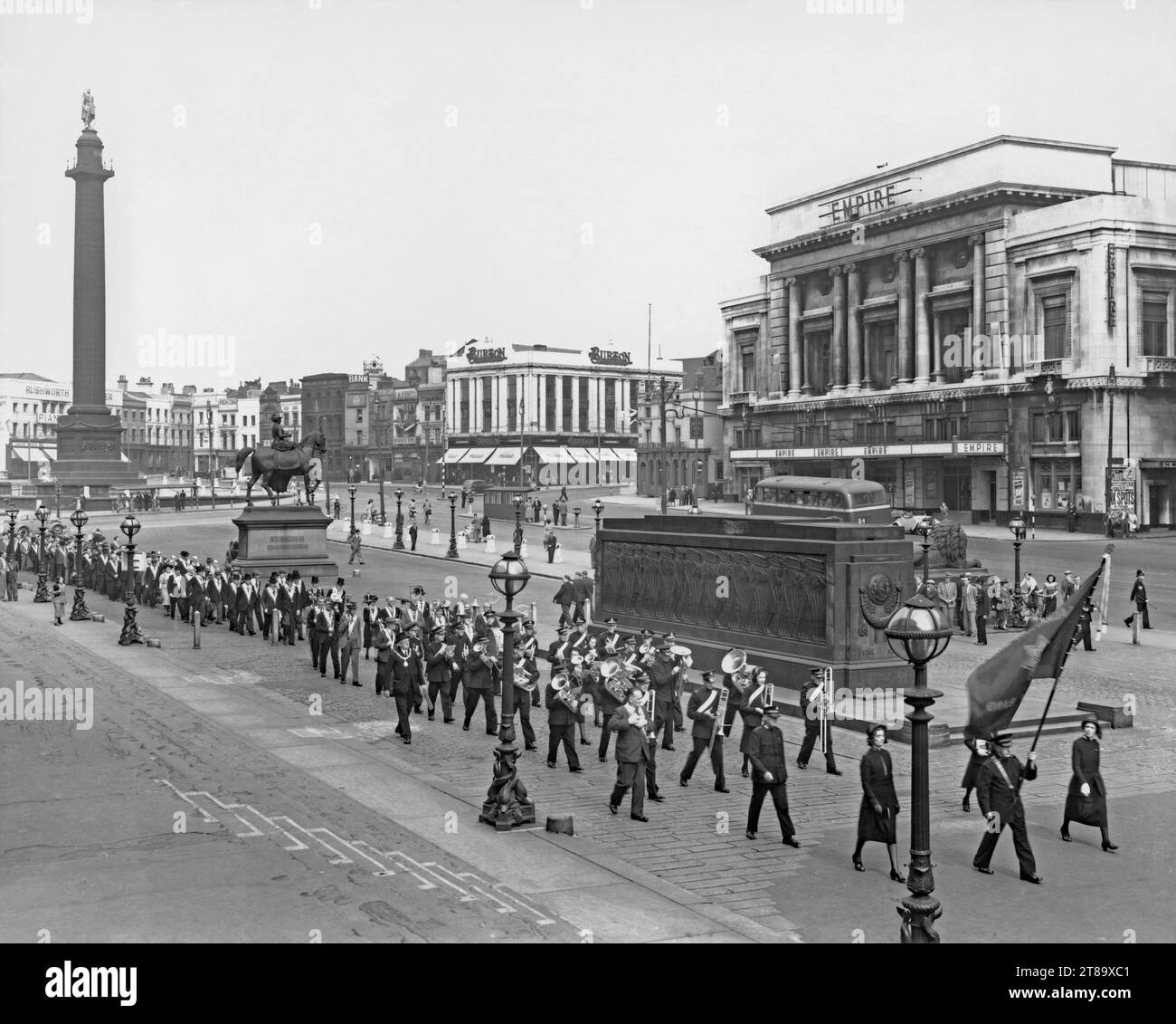 A march taking place in Lime Street, Liverpool, Merseyside, England, UK c.1950. The march is headed by the Salvation Army band, followed by Freemasons (holding aloft their symbols – such as the all-seeing eye, the beehive and blazing star). They walk alongside the steps of St Georges Hall, passing Wellington’s Column (left), the Queen Victoria Equestrian statue (centre) and the Liverpool Cenotaph (right). Behind is the Liverpool Empire Theatre (opened in 1925). A poster indicates that the American group The Ink Spots were to appear at the venue – a vintage 1940s/50s photograph. Stock Photo