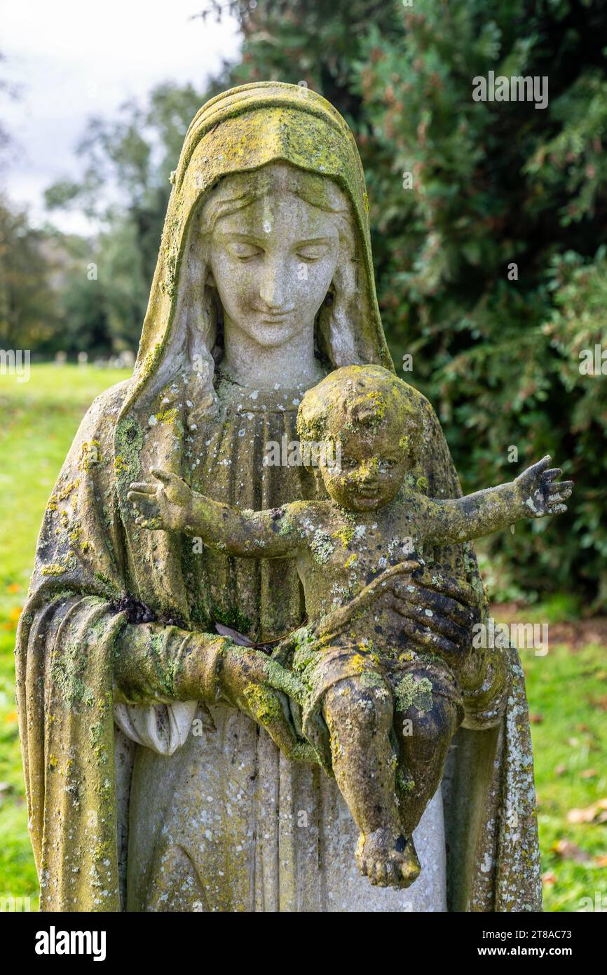 Green lichen growing on stone memorial statue of Mary and baby Jesus