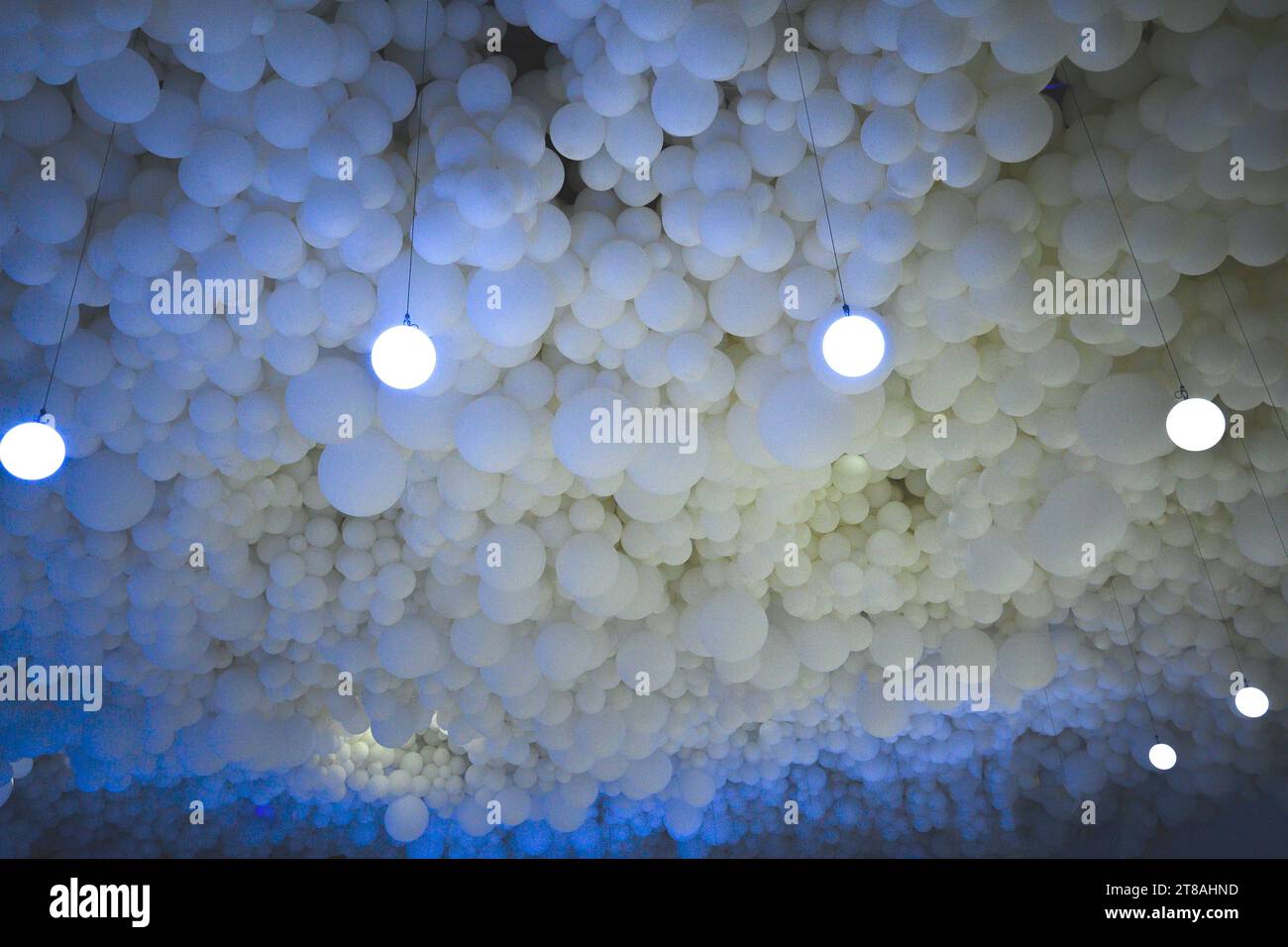 Ceiling of white spheres of numerous balloons with artificial light imitating sky of fluffy clouds Stock Photo