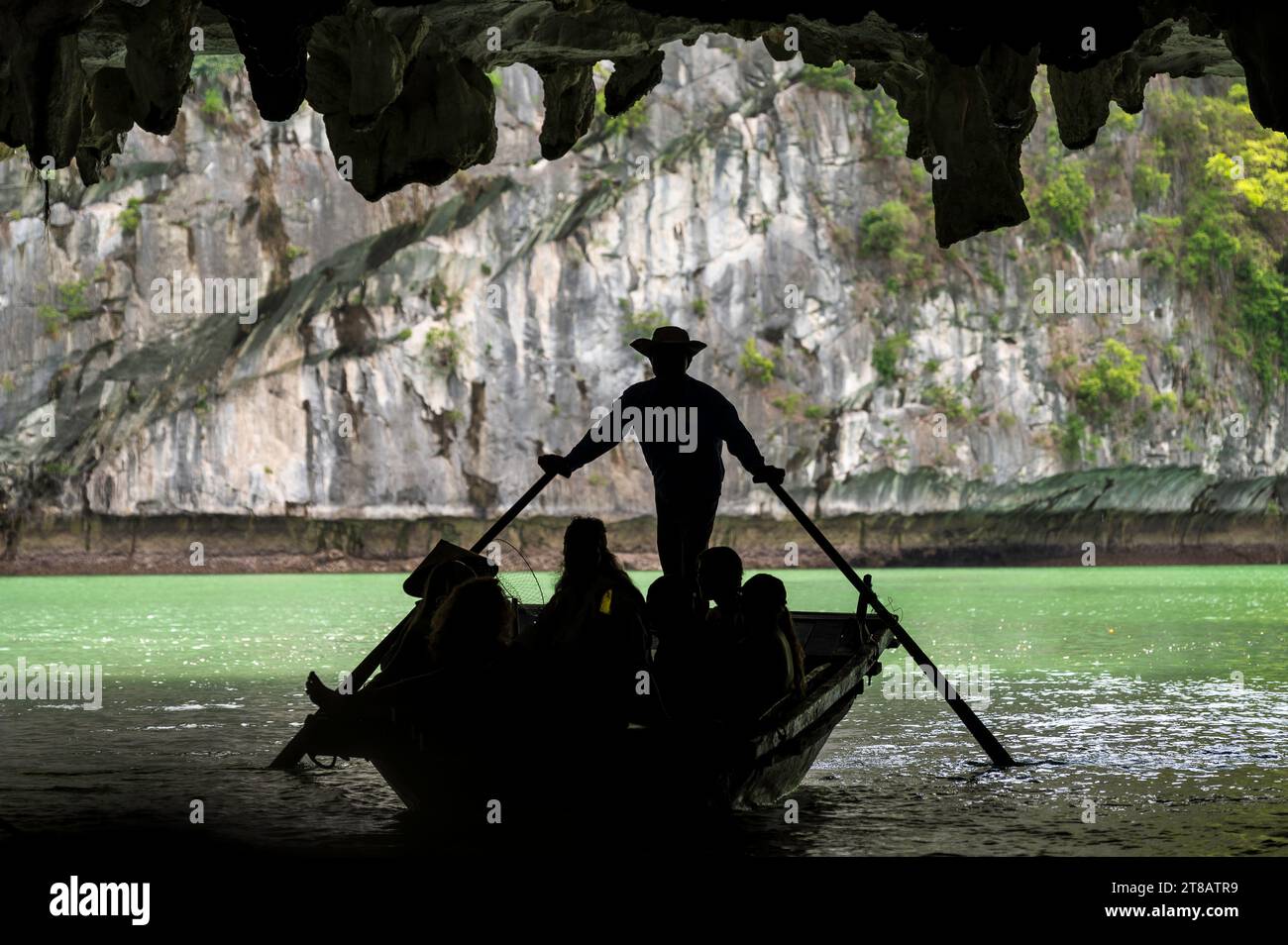 Sihouette of a rowing boat in the dark caves of Halong Bay, Vietnam. Rowing boats take tourists to see the geology of the area up close. Stock Photo