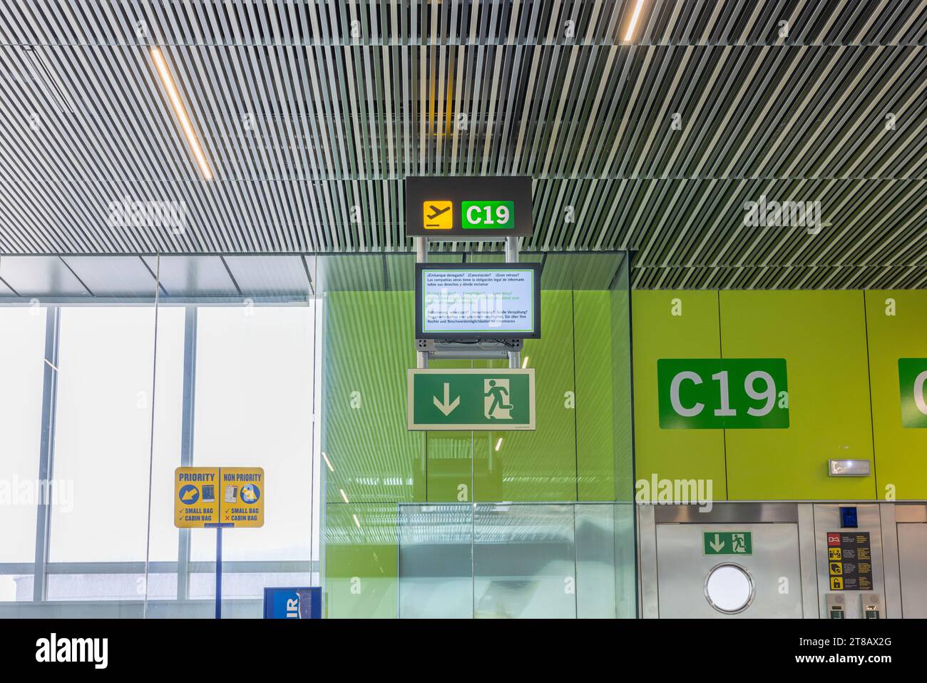 View of information display board and signs located above one of boarding gates at airport, providing details for passengers about their flight. Gran Stock Photo
