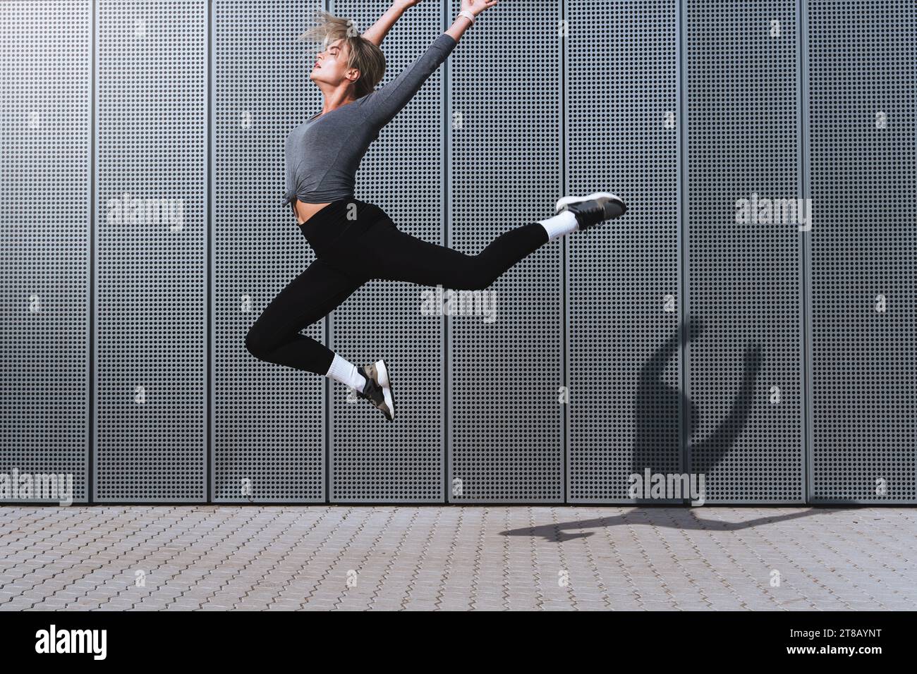 Woman dancer wearing female sportswear performing against background with modern steel panels Stock Photo