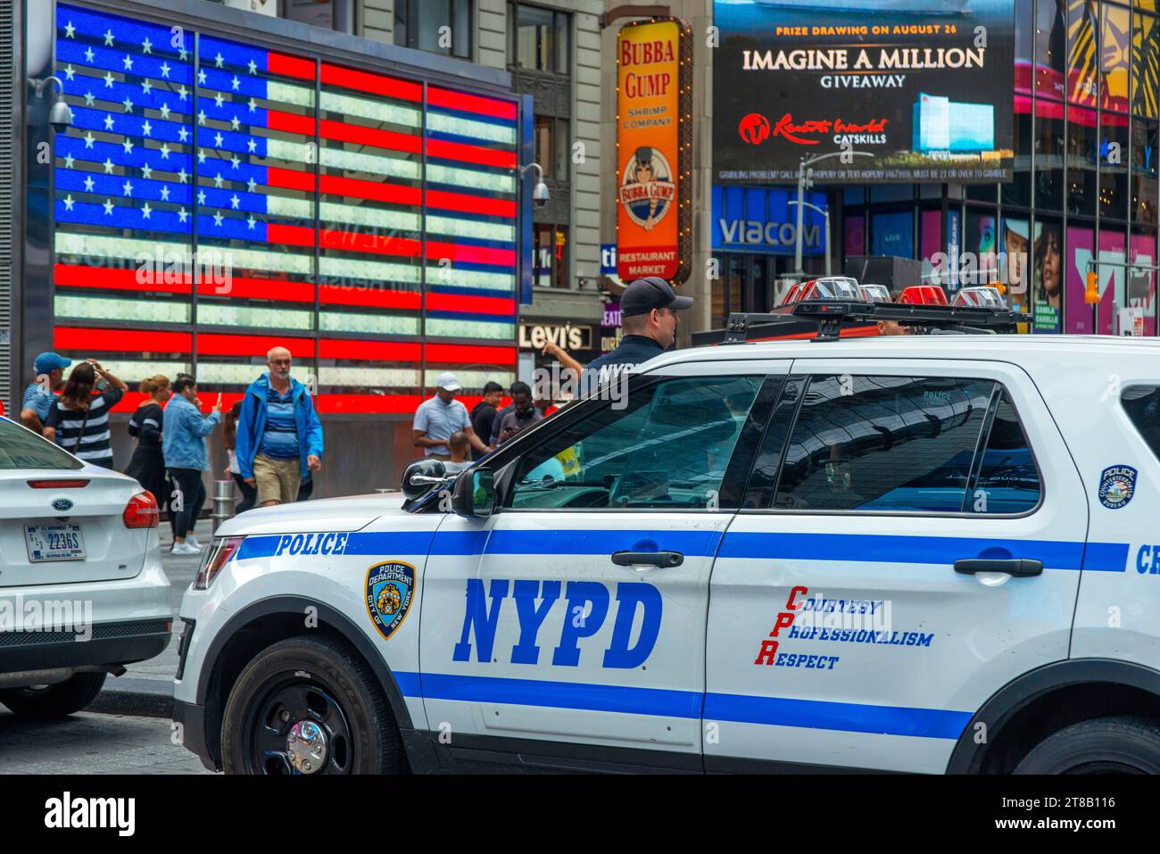 Big american flag and New York City Police Department Emergency Service Unit officer on Wall Street in New York City New York USA Stock Photo