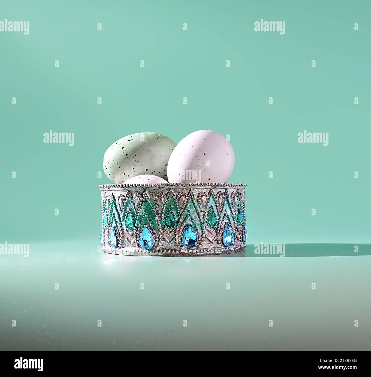 Easter Treasure Trove: A Jeweled, Radiant Container with Pastel Colored Easter Eggs on a Green Background Stock Photo