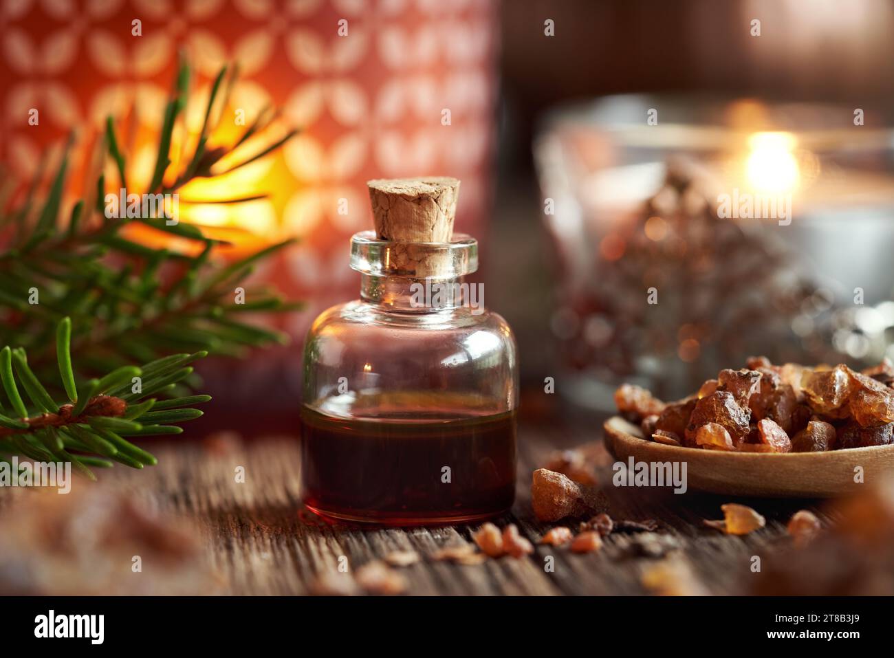 A transparent bottle of myrrh essential oil with spruce branches and candle at Christmas Stock Photo