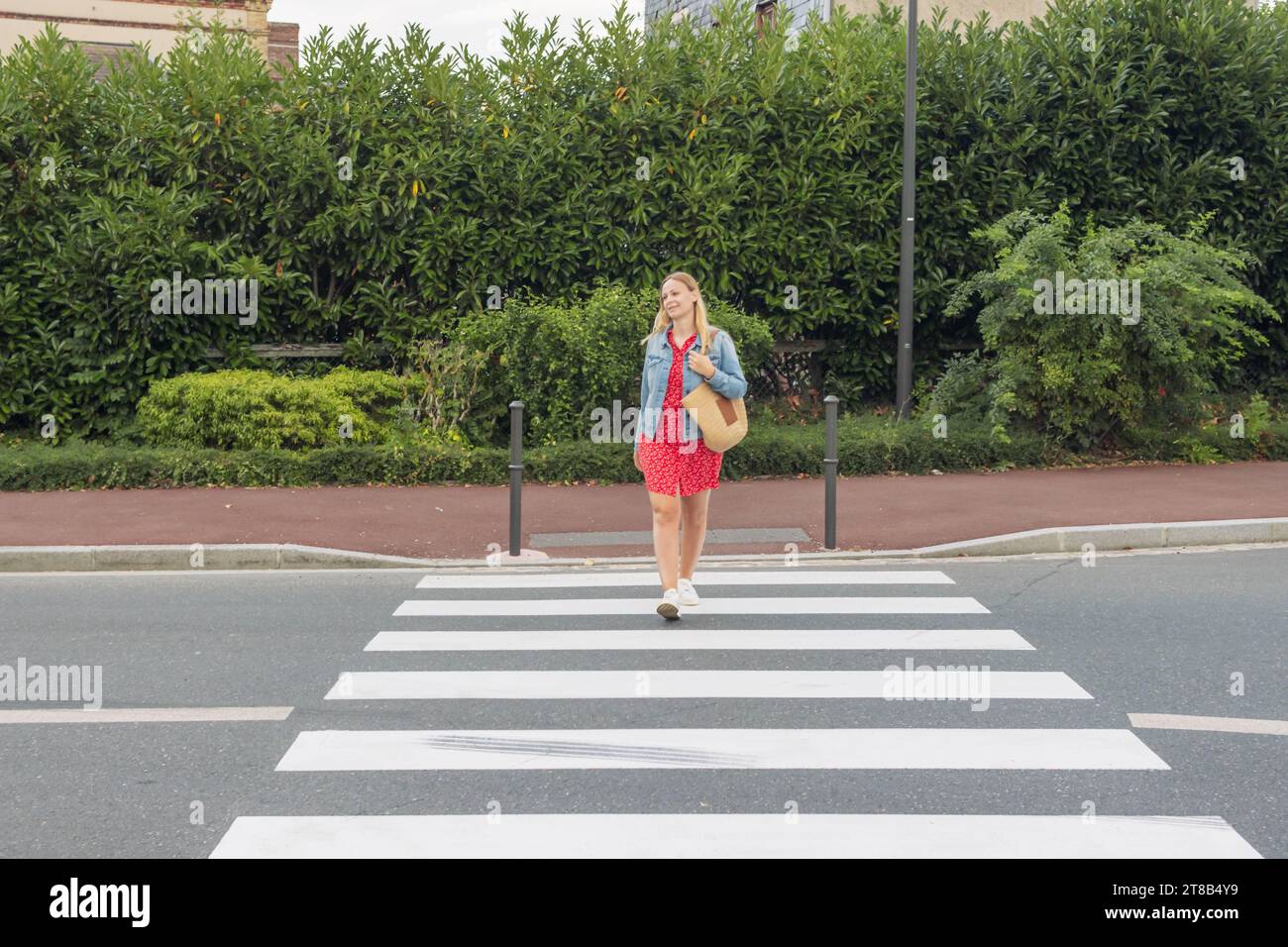 a girl in a red dress crosses the road at a pedestrian crossing ...