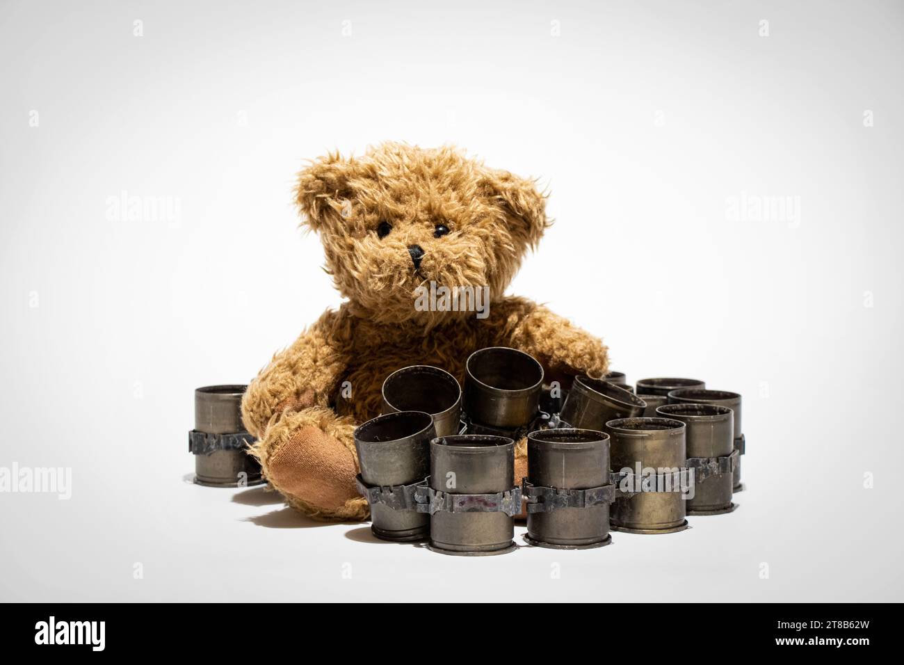 Automatic grenade launcher casing tape and teddy bear on a white background, explosive shell fired during the war in Ukraine, weapon Stock Photo