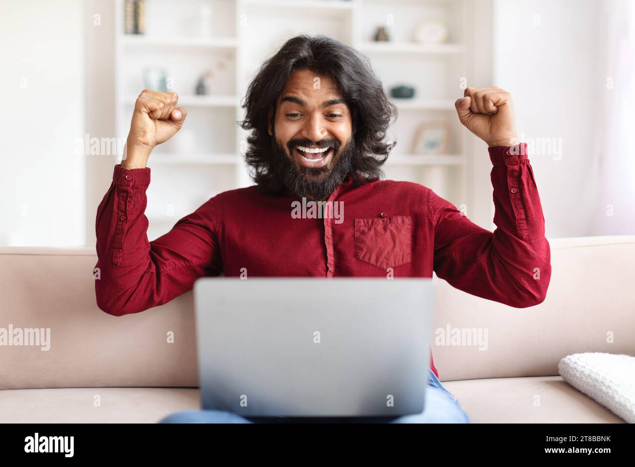 Emotional indian man using computer at home Stock Photo