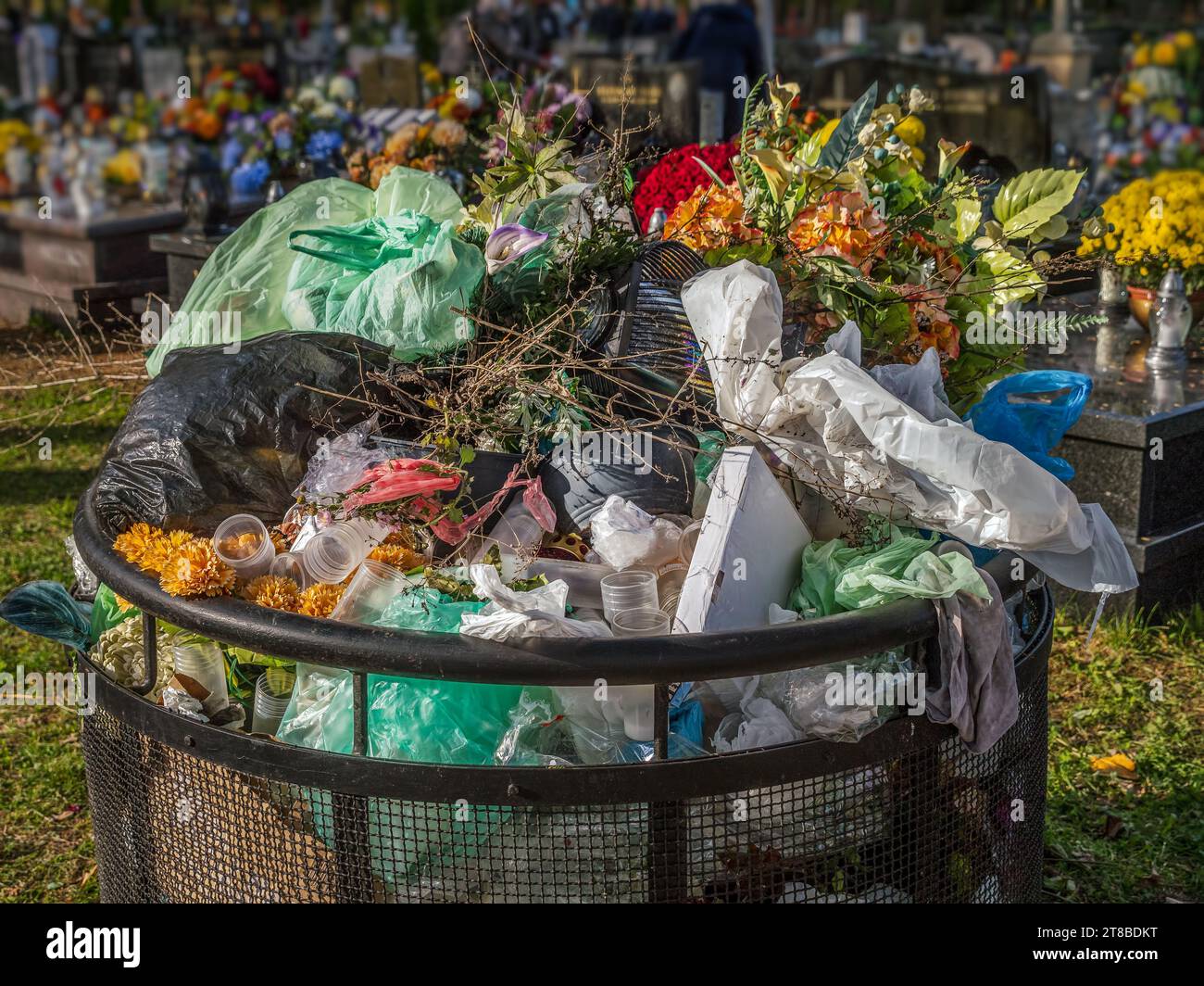 Cemetary trash bin filled with tombstone waste decorations and rubbish Stock Photo