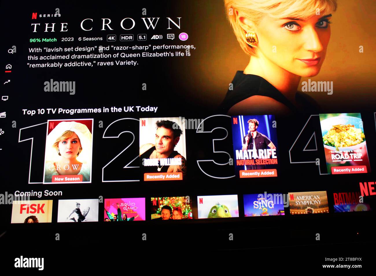 Netflix application on tv screen highlighting the Netflix television show The Crown with the shadow of someone holding a TV remote in front. Stock Photo