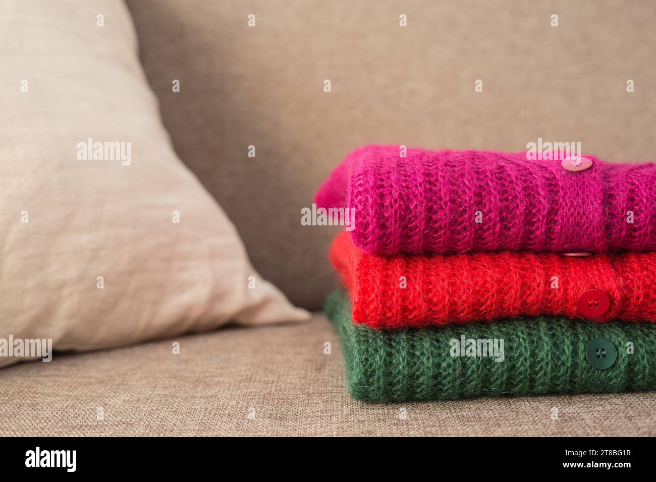 Stack of folded mohair cardigans in red, cherry and green colors. Cashmere Soft and fluffy wool. Stacked knitting patterns. Wool fabric Stock Photo