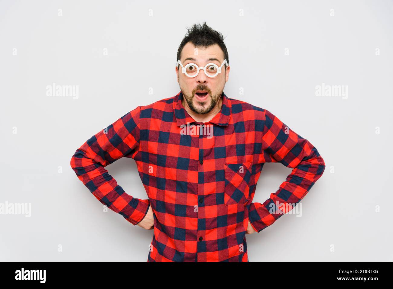 Wow, Incredible! Funny Amazed Shocked Surprised Portrait Man with Glasses with Mouth Open. Man on a light background is wearing a red checkered shirt Stock Photo