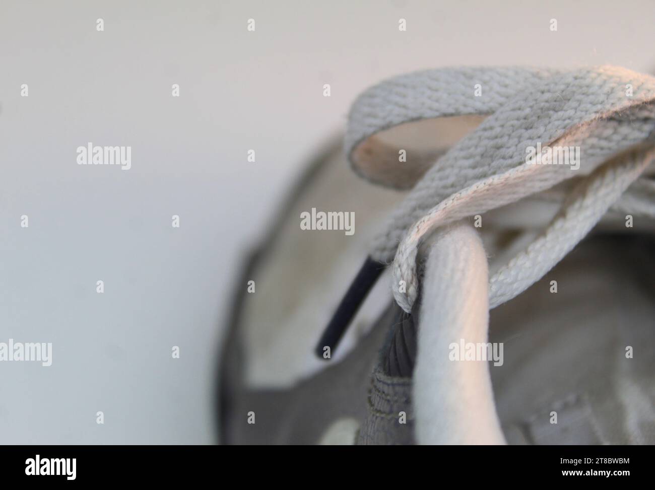 A close up photo of the shoelaces of white dirty Nike Air Max 90 Runners on a white desk. Stock Photo