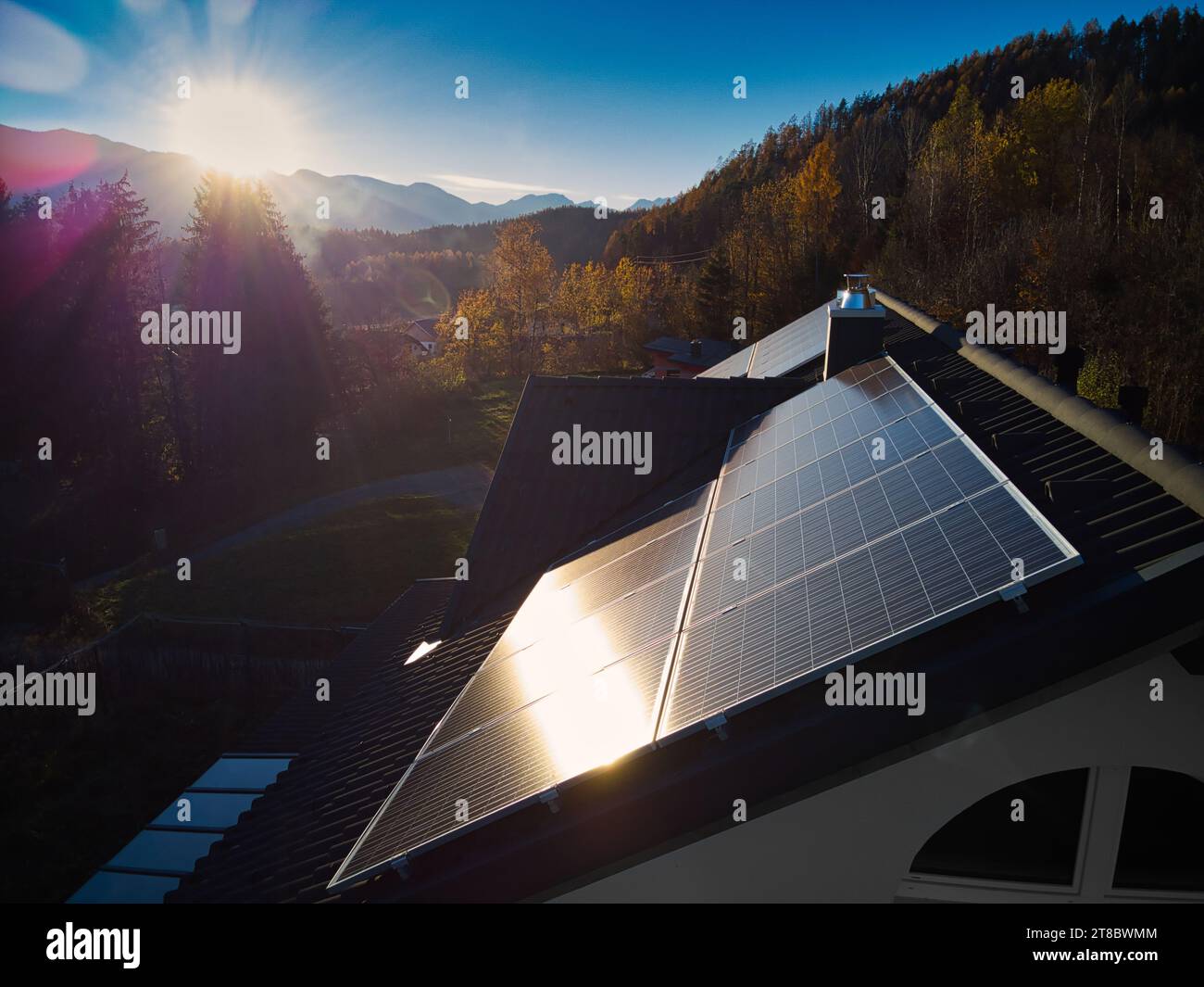 Experience sustainable living with photovoltaic panels on a private residence's rooftop, captured from a captivating drone perspective in the warm eve Stock Photo