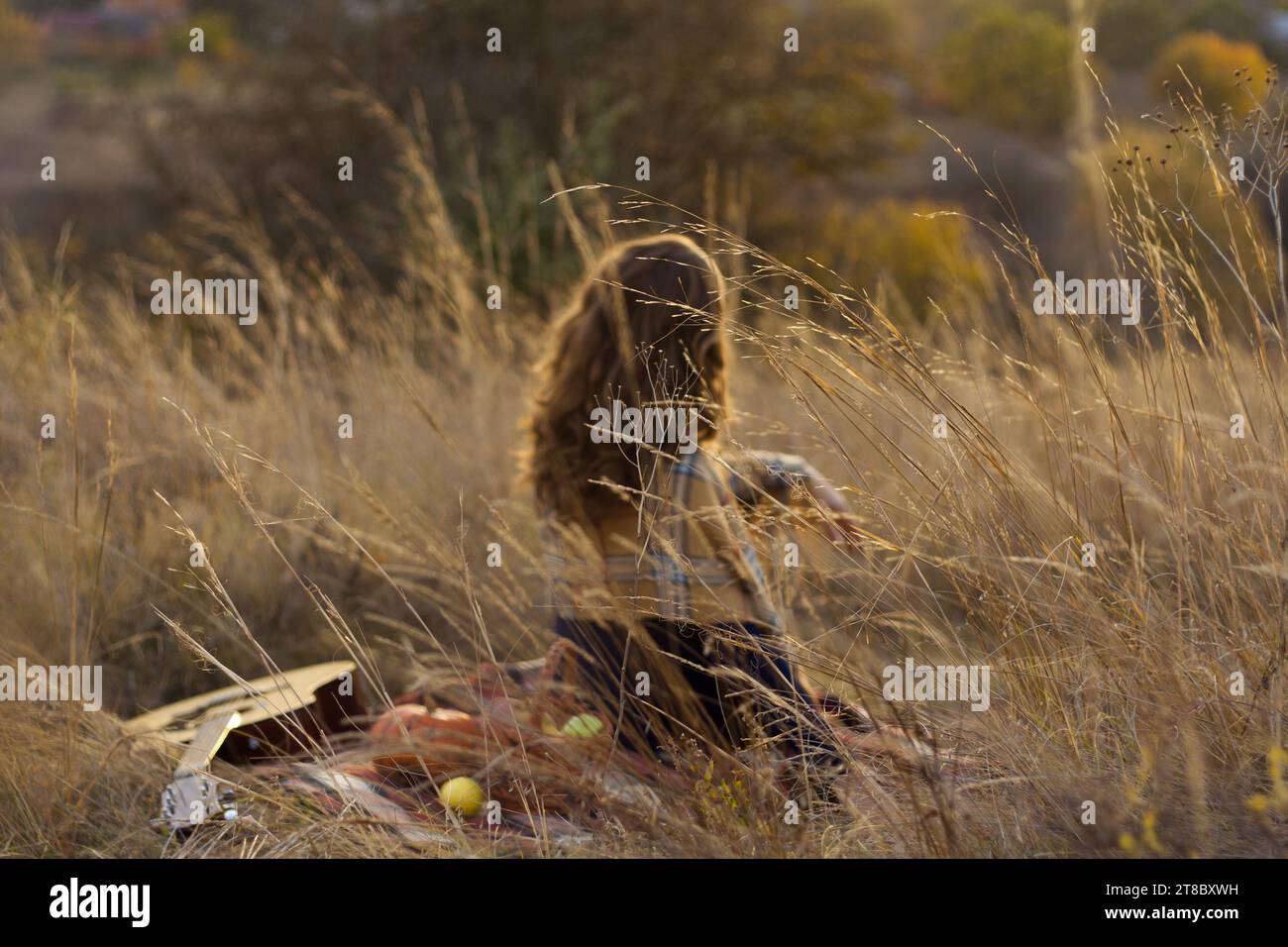 beautiful young woman musician finished playing melody on acoustic guitar and relaxing, sitting in field, enjoying autumn sunset. Outdoor Picnic. Roma Stock Photo