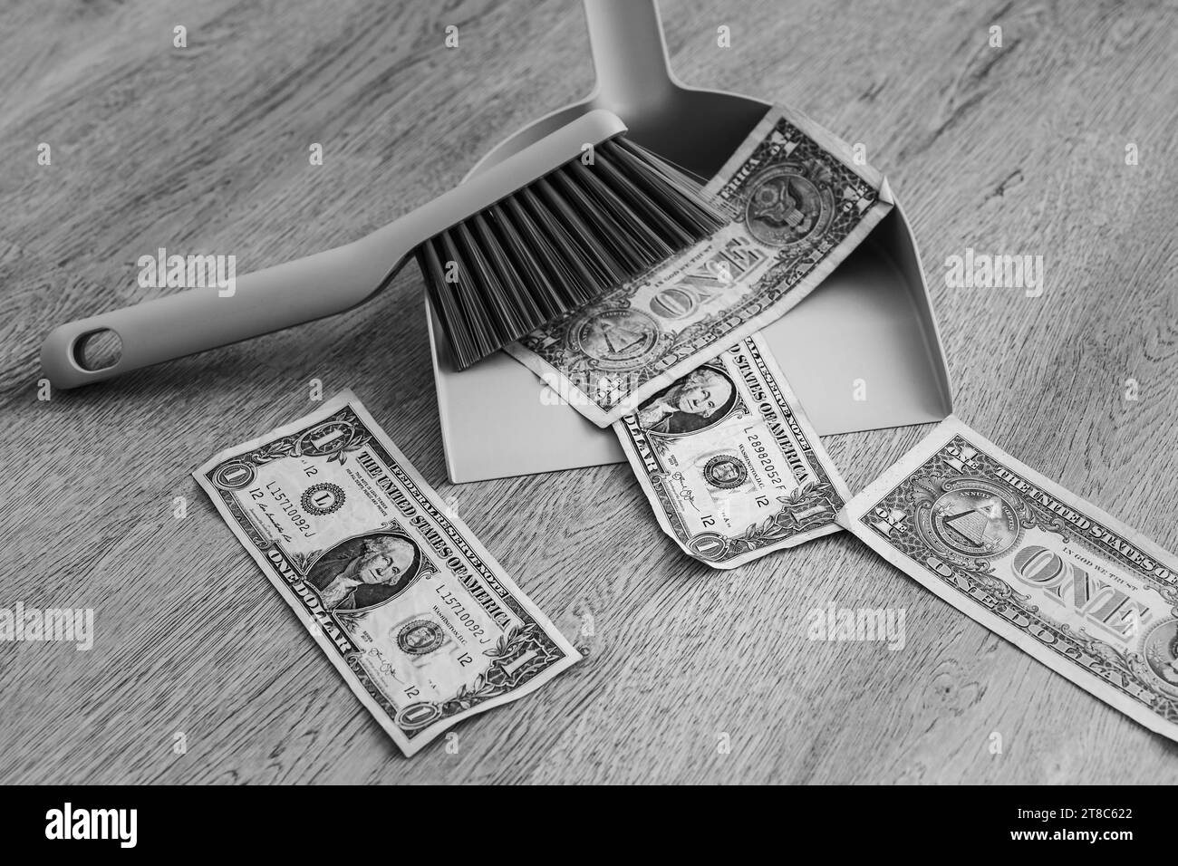 Dustpan and brush alongside scattered one-dollar bills on the floor Stock Photo