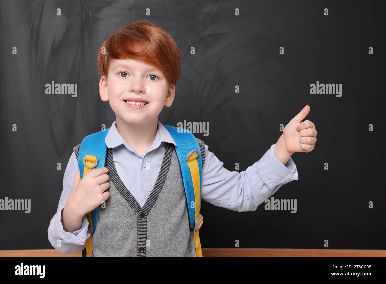 Smiling schoolboy showing thumb up near blackboard Stock Photo - Alamy