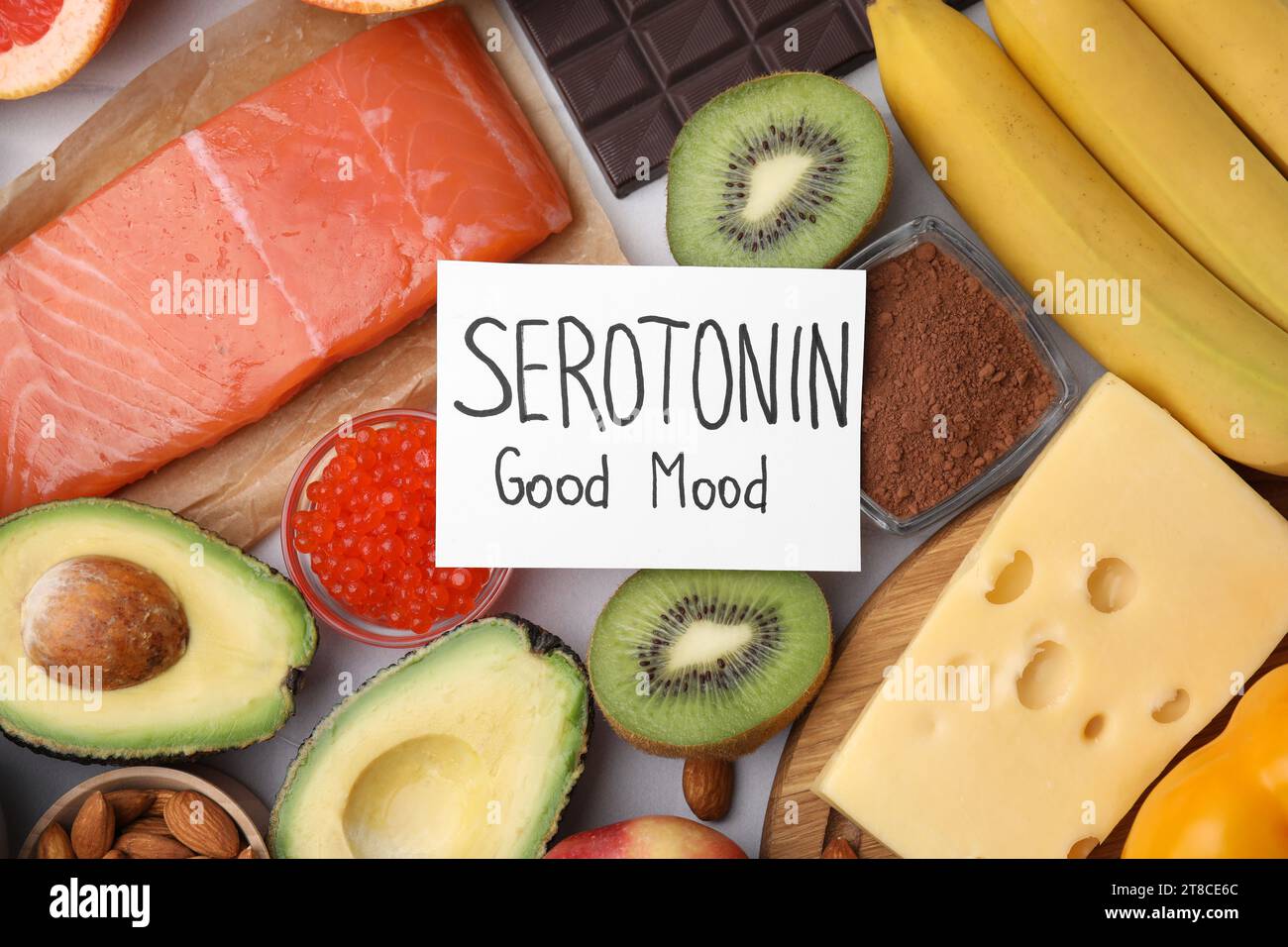 Many different products and card with phrase Serotonin Good Mood on white table, flat lay. Natural antidepressants Stock Photo
