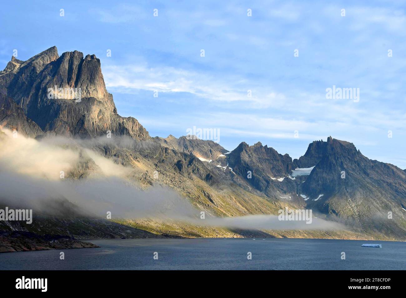 the steep, glaciated granite peaks of the western side of the prince christian sound and wisps of fog, in southern greenland, from a cruise ship Stock Photo