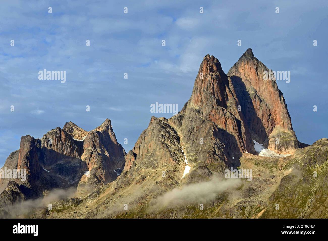 the steep, glaciated granite peaks of the western side of the prince christian sound and wisps of fog, in southern greenland, from a cruise ship Stock Photo