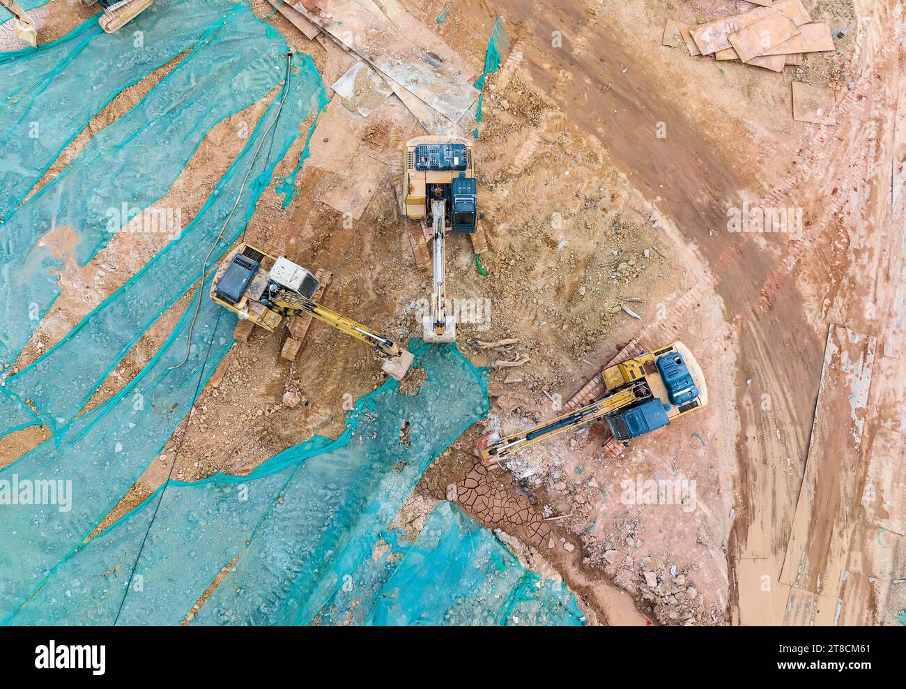Large tracked excavator with hydraulic hammer breaks asphalt at a construction site Stock Photo