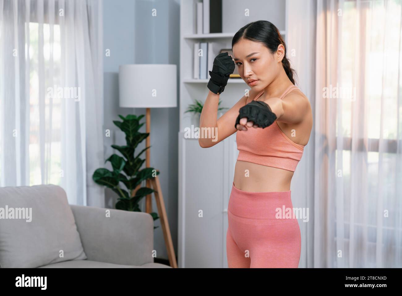 Fit young asian woman portrait in sportswear preparing herself before healthy exercising routine at home. Domestic fitness workout training on living Stock Photo