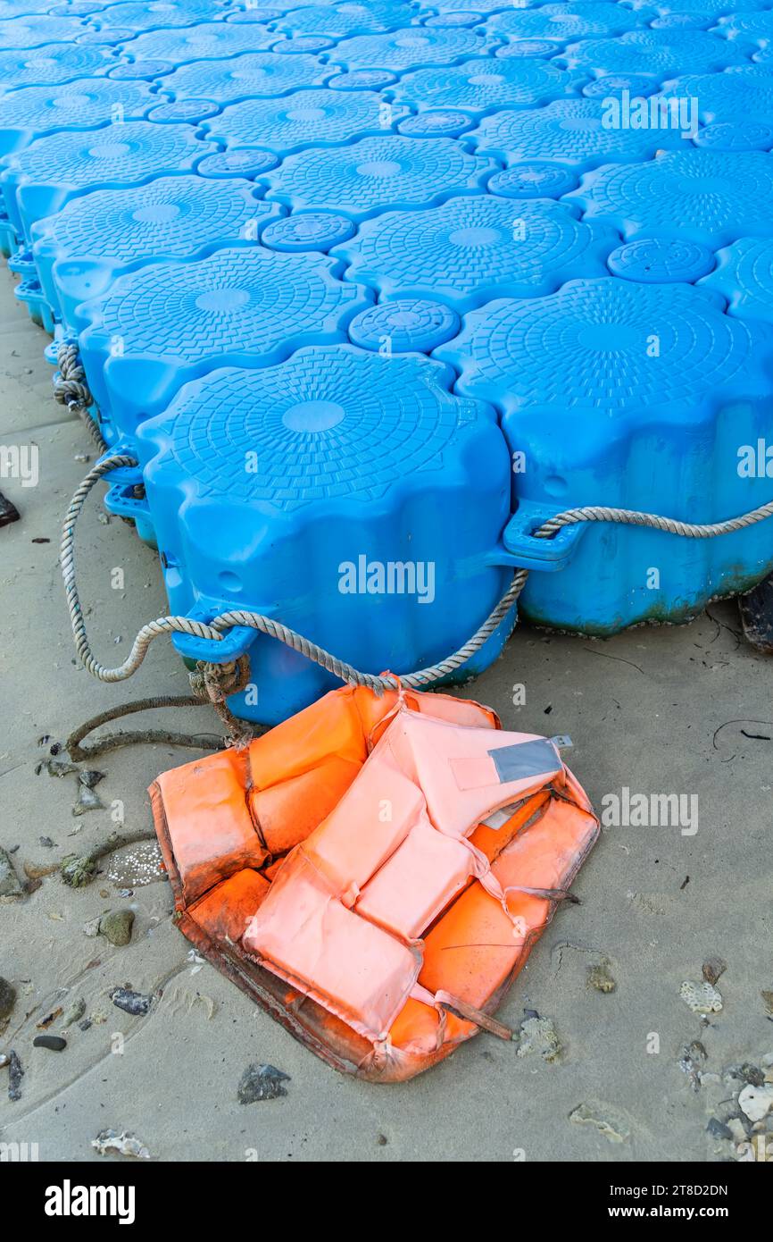 Dilapidated old floating plastic pontoon platform with life jacket