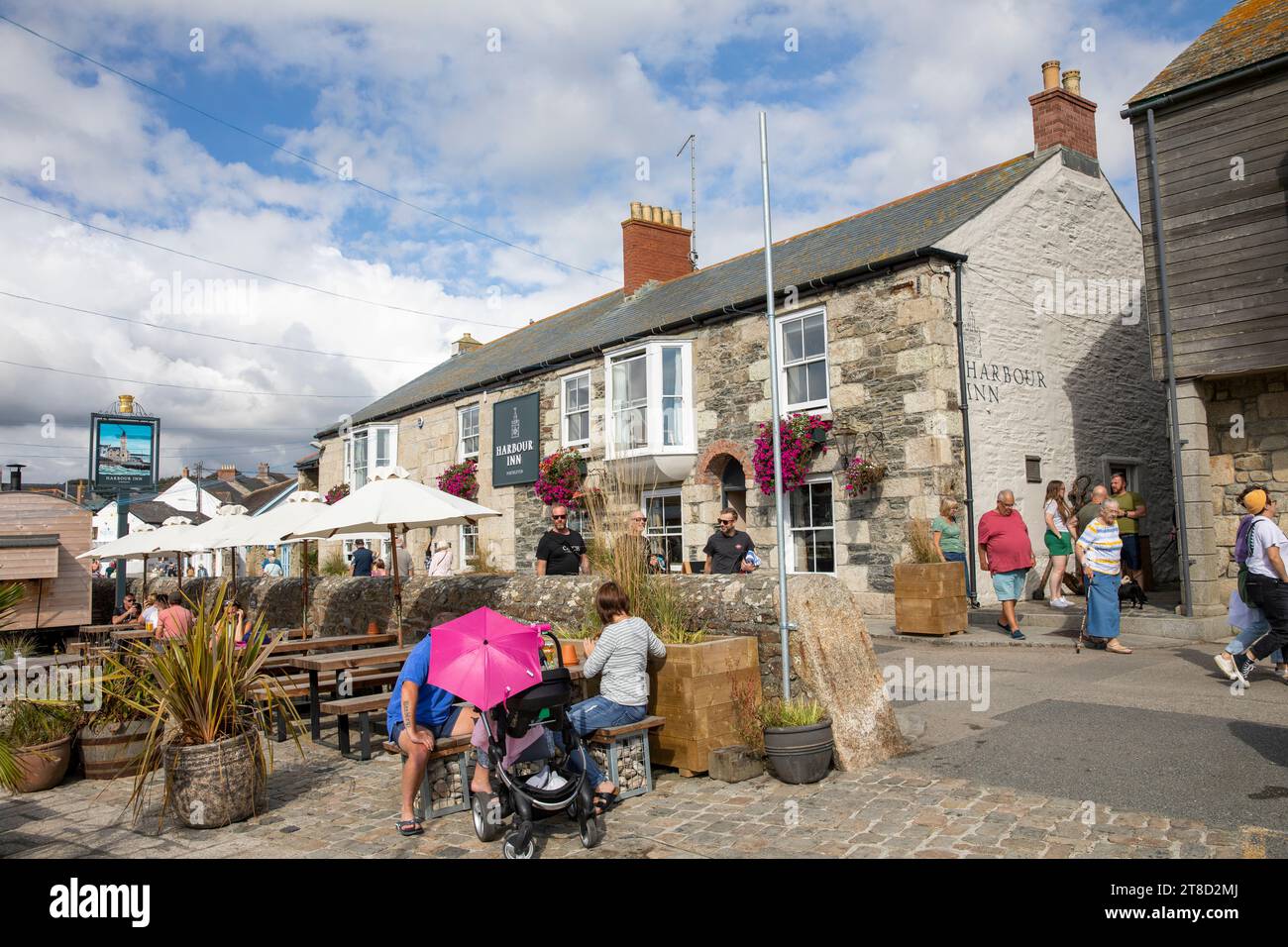People sitting outside English pub,The Harbour Inn in Porthleven Cornwall, sunny autumn day 2023,England,Uk Stock Photo