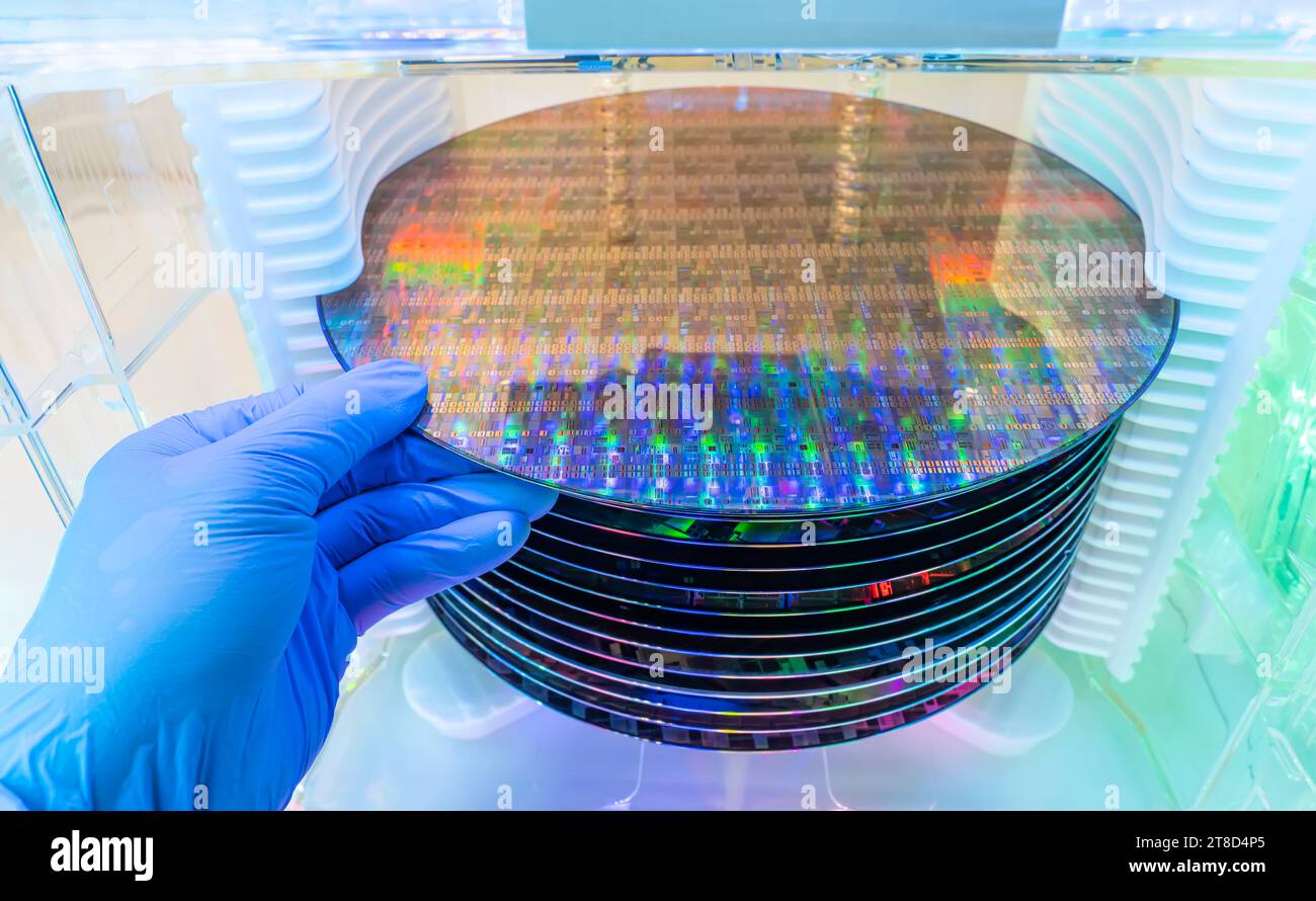Gloved Hand Holding a Silicon Wafer in plastic holder box used in electronics for the fabrication of integrated circuits Stock Photo