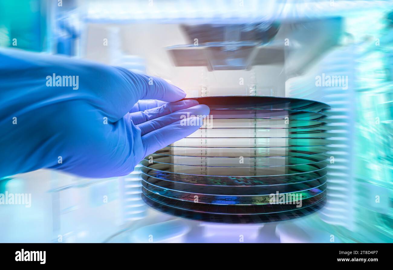 Gloved Hand Holding a Silicon Wafer in plastic holder box used in electronics for the fabrication of integrated circuits Stock Photo
