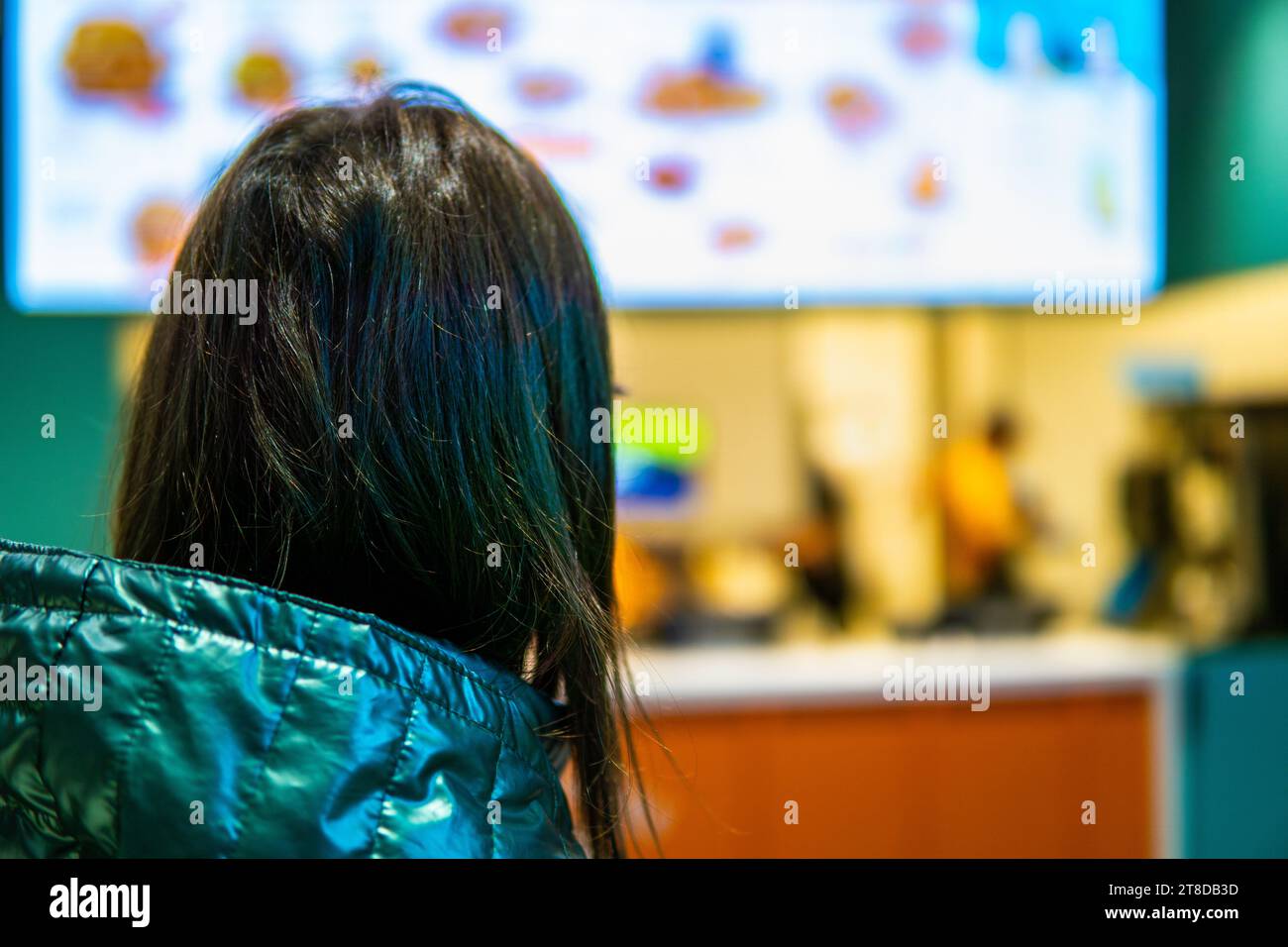 Woman in fast food chain restaurant looking at menu display Stock Photo