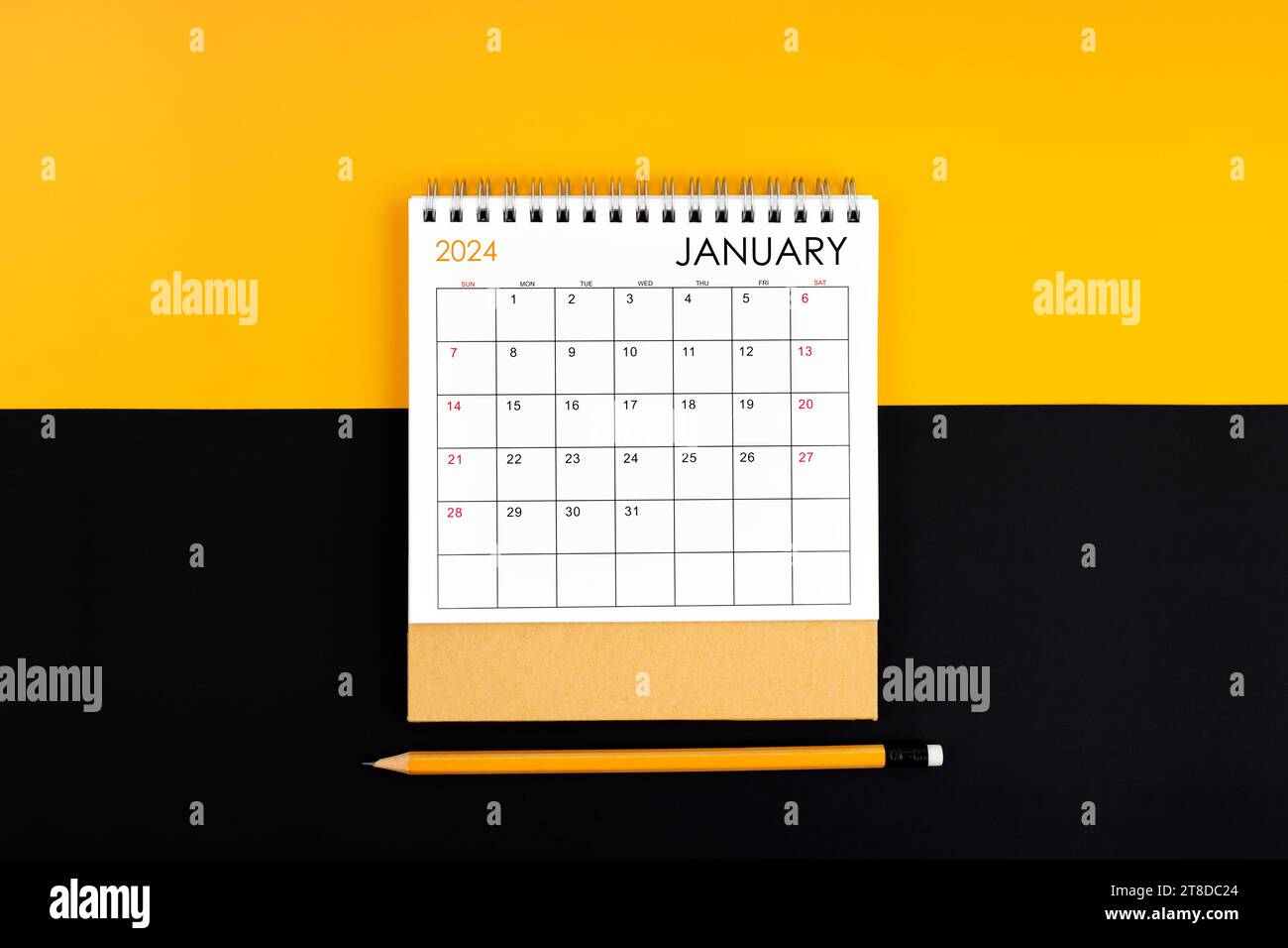 Top view of January 2024 desk calendar and pencil on yellow and black ...