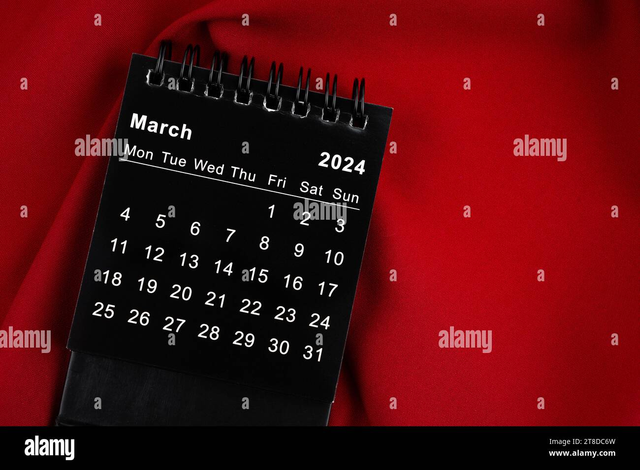 March 2024 Black spiral desktop calendar on red textile Stock Photo - Alamy
