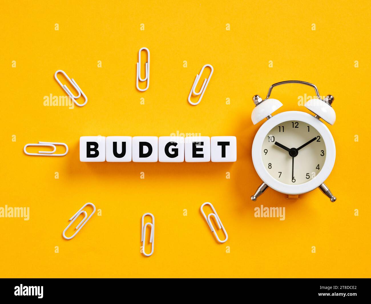 The word budget on cubes with alarm clock and paper clips. Budget planning. Budgeting and financial planning. Stock Photo