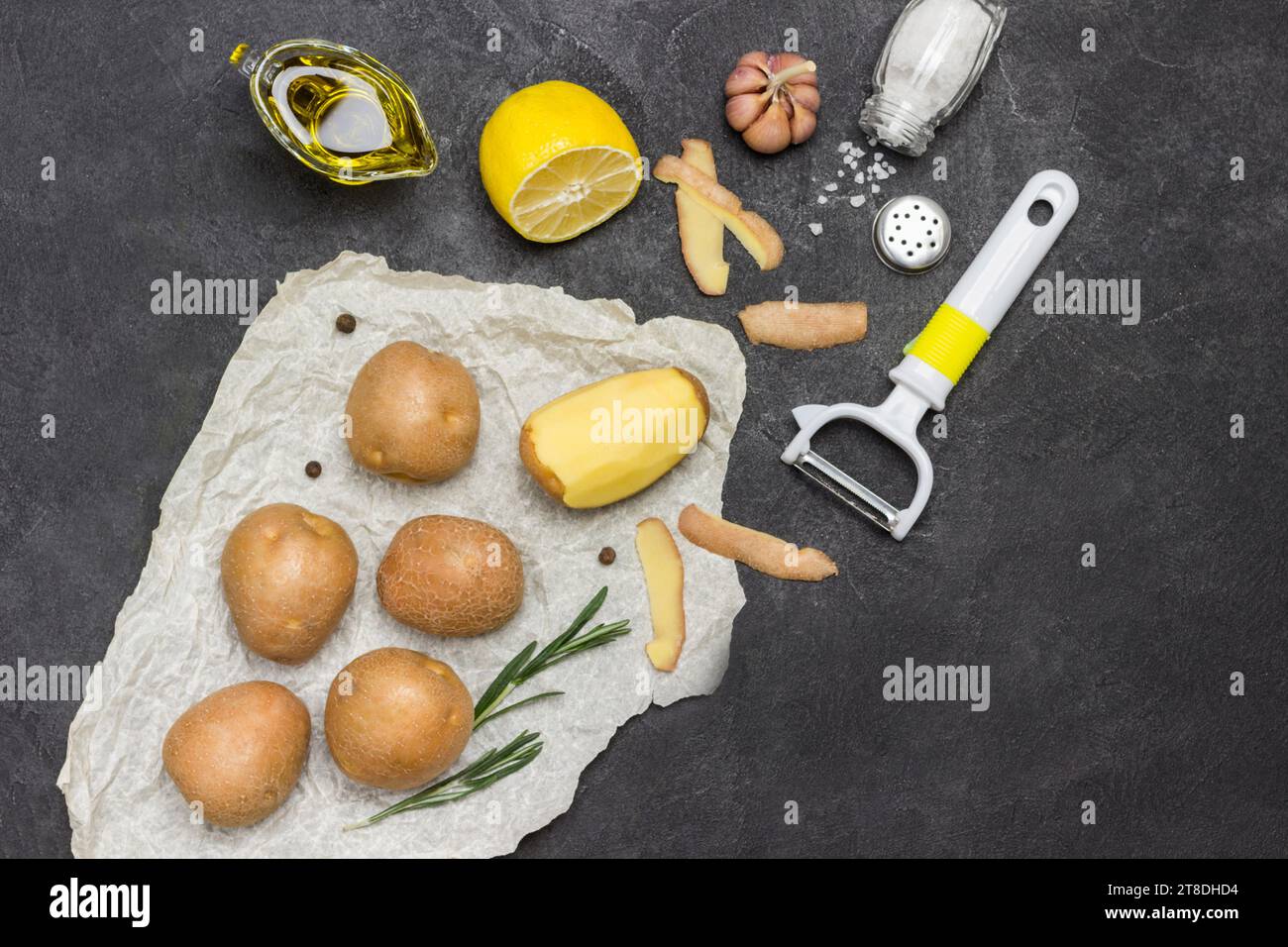 https://c8.alamy.com/comp/2T8DHD4/raw-potatoes-and-one-peeled-potato-on-white-paper-with-rosemary-green-pepper-and-lemon-black-background-flat-lay-copy-space-2T8DHD4.jpg