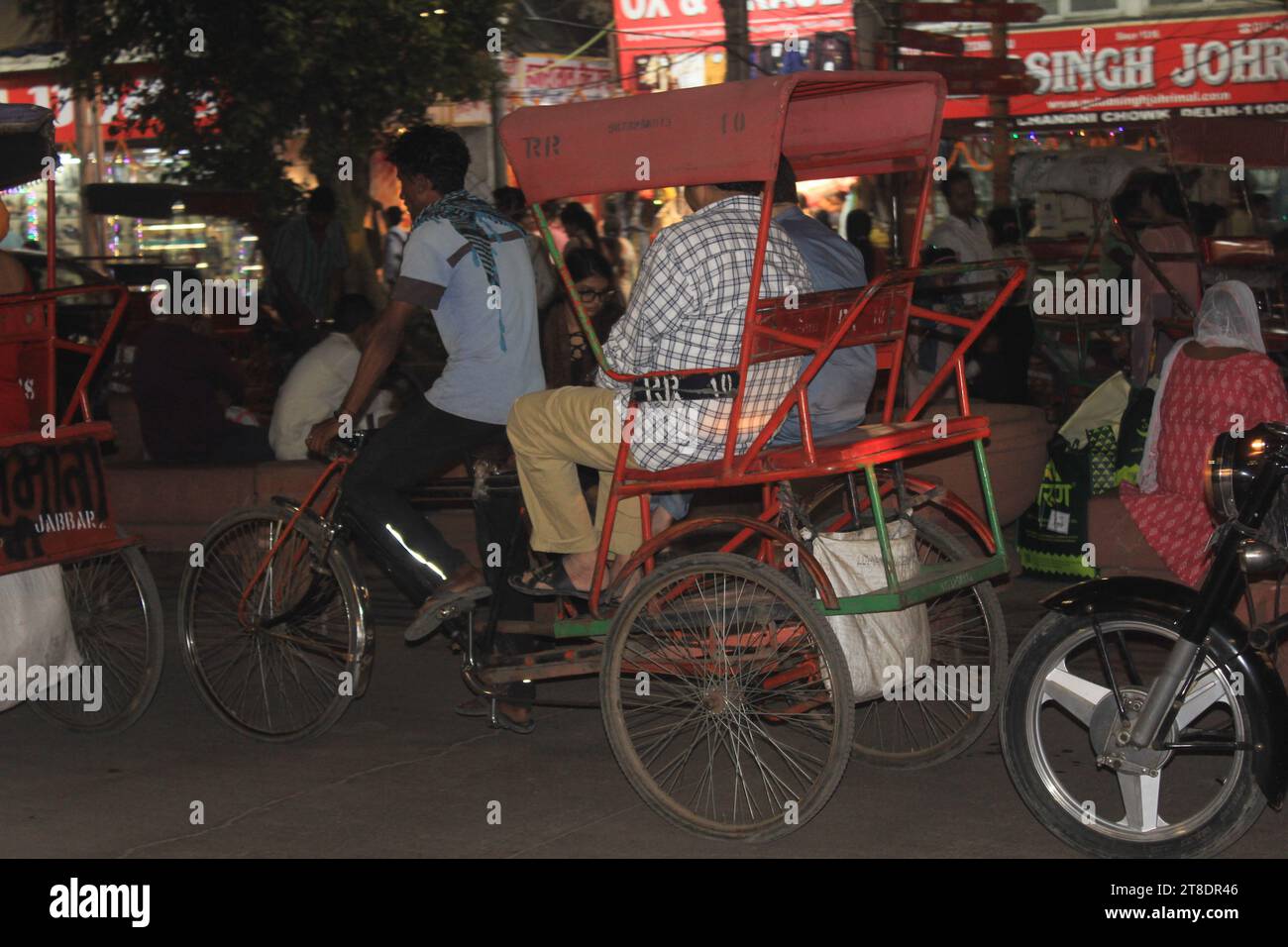 An unknown rickshaw puller working during night time on the streets of Chandni Chowk market in New Delhi, India on 14th November, 2023. Stock Photo
