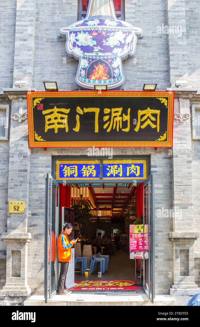 Young woman standing in the entrance of a shop in Beijing, China Stock Photo