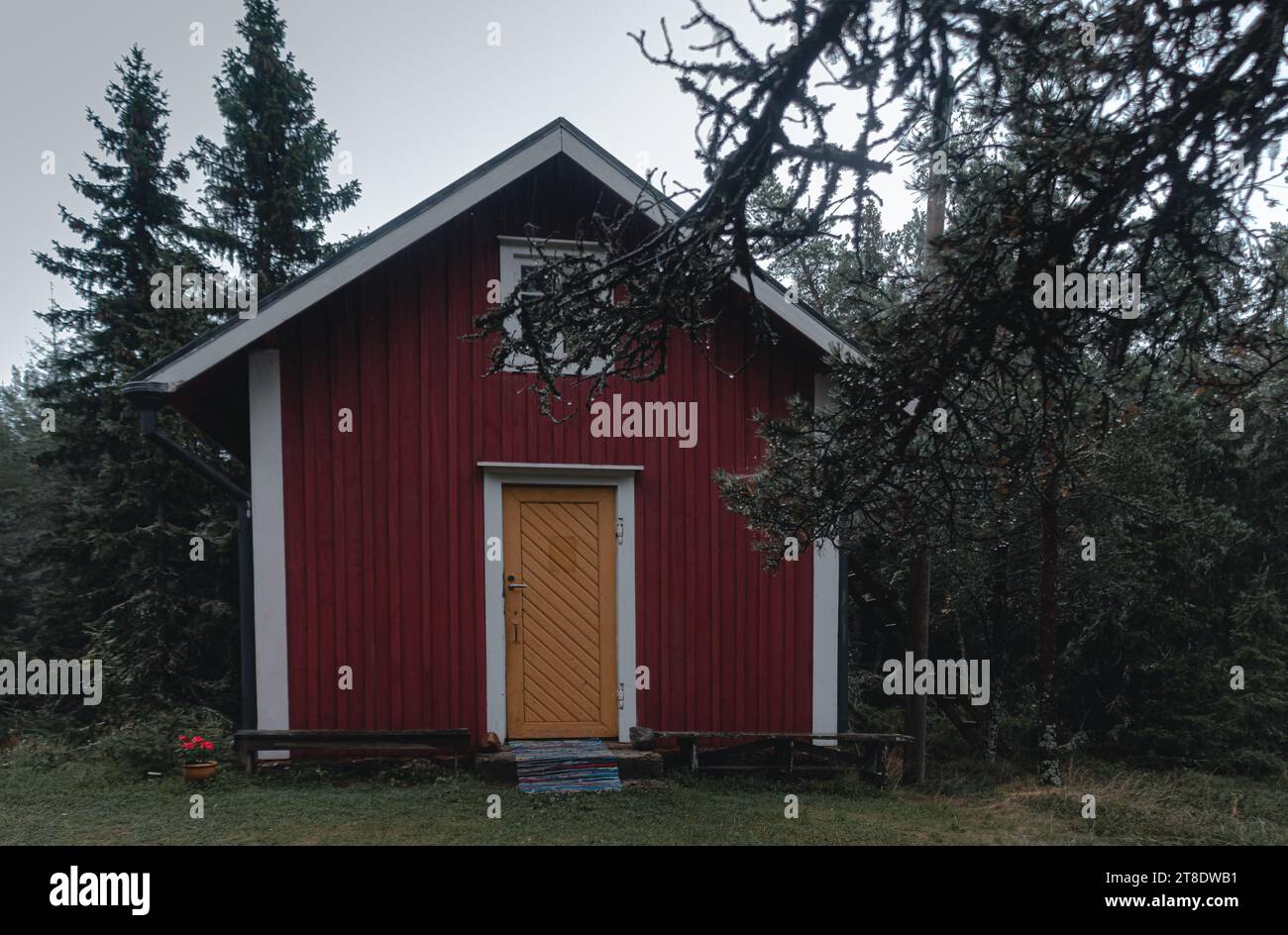 red house and an old wooden hut in a forest in a country area. Stock Photo