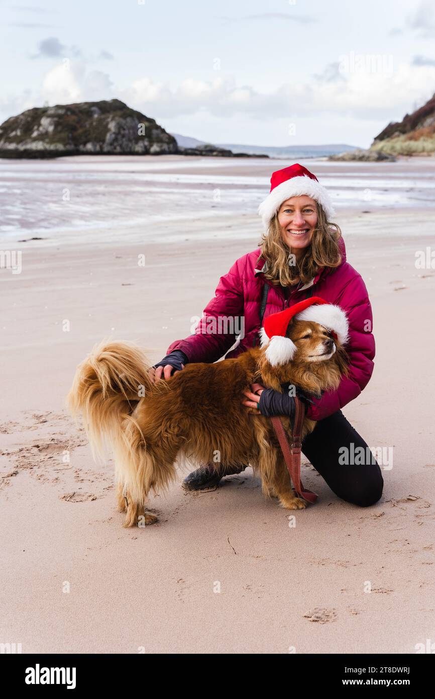 Female and dog wearing Santa hats on beach Stock Photo - Alamy