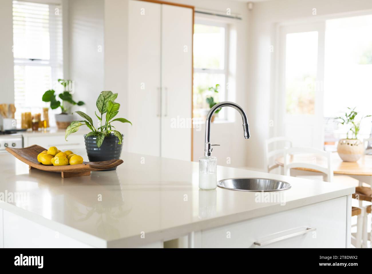 Kitchen island, sink, furniture and large windows in sunny kitchen at home Stock Photo
