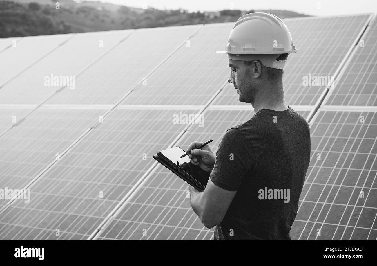 Engineer working at solar panels factory outdoor - Photovoltaic, renewable green energy and environmental concept - Focus on face - Black and white ed Stock Photo
