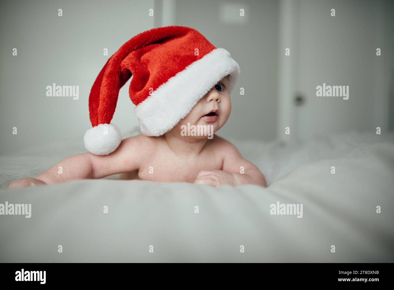 Close up of baby boy wearing christmas Santa hat falling over on Stock Photo