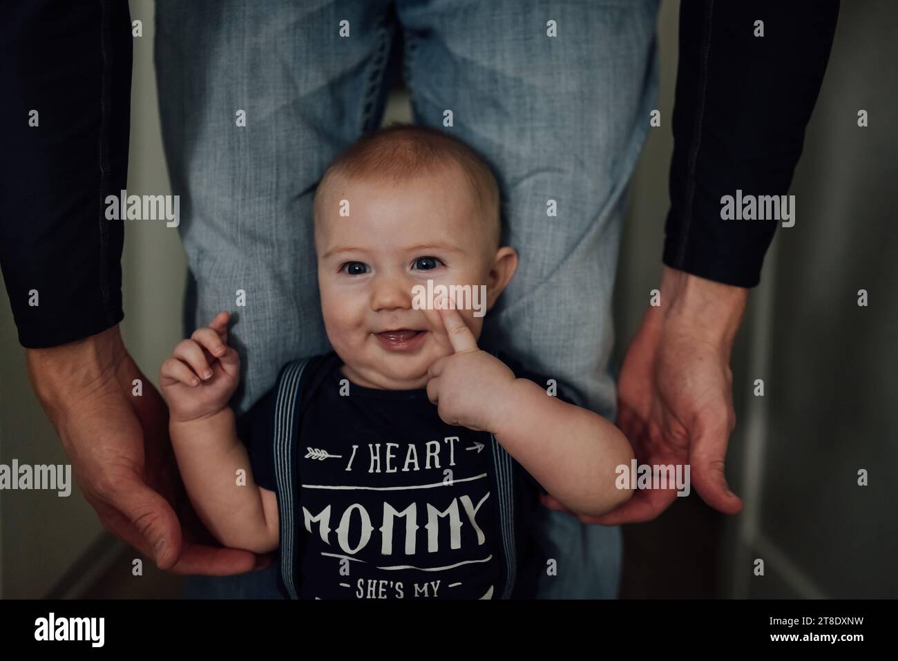 Close up of baby boy laughing and touching face while dad holds Stock Photo